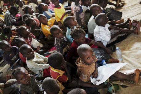Children, seated on canvas covering the floor of a crowded classroom, attend a UNICEF-supported school in the Boy Rabe Monastery displacement camp in Bangui, the capital. © UNICEF/NYHQ2014-0326/Grarup; 