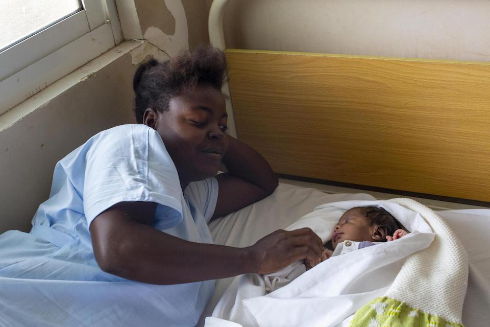 A mother rests beside her day-old son after he has received his newborn vaccinations at UNICEF-supported Benfica Maternal and Child Health Center in Luanda, Angola. .  