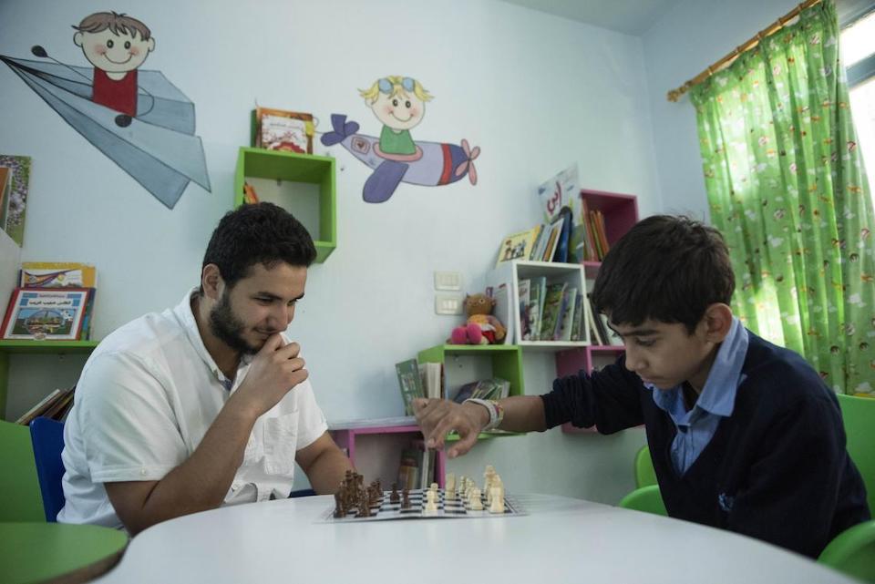 Osama, 14, plays chess with Nour, a volunteer in a UNICEF-supported center in Altal city, Rural Damascus.