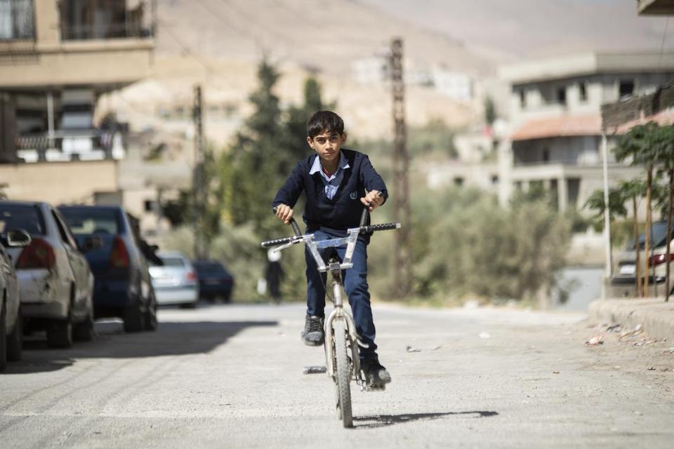 Osama, 14, rides his bicycle on his way to a UNICEF-supported center in Altal city, Rural Damascus.